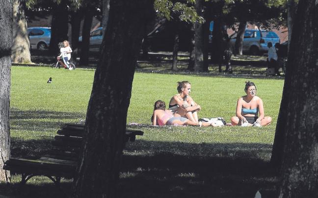 Tres j&oacute;venes toman el sol en la Vuelta del Castillo de Pamplona.
