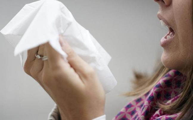 Una persona estornuda con un catarro otoñal