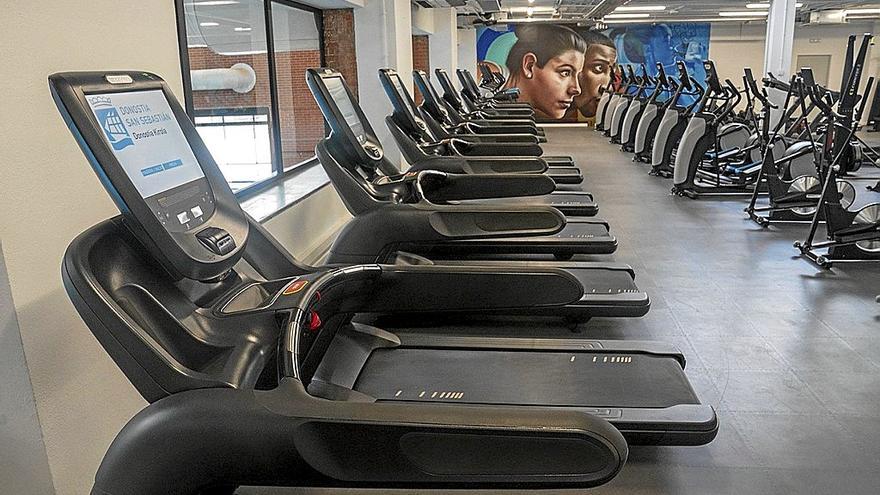 Máquinas deportivas en el nuevo gimnasio del polideportivo Paco Yoldi, con un mural de Nextor Otaño al fondo.