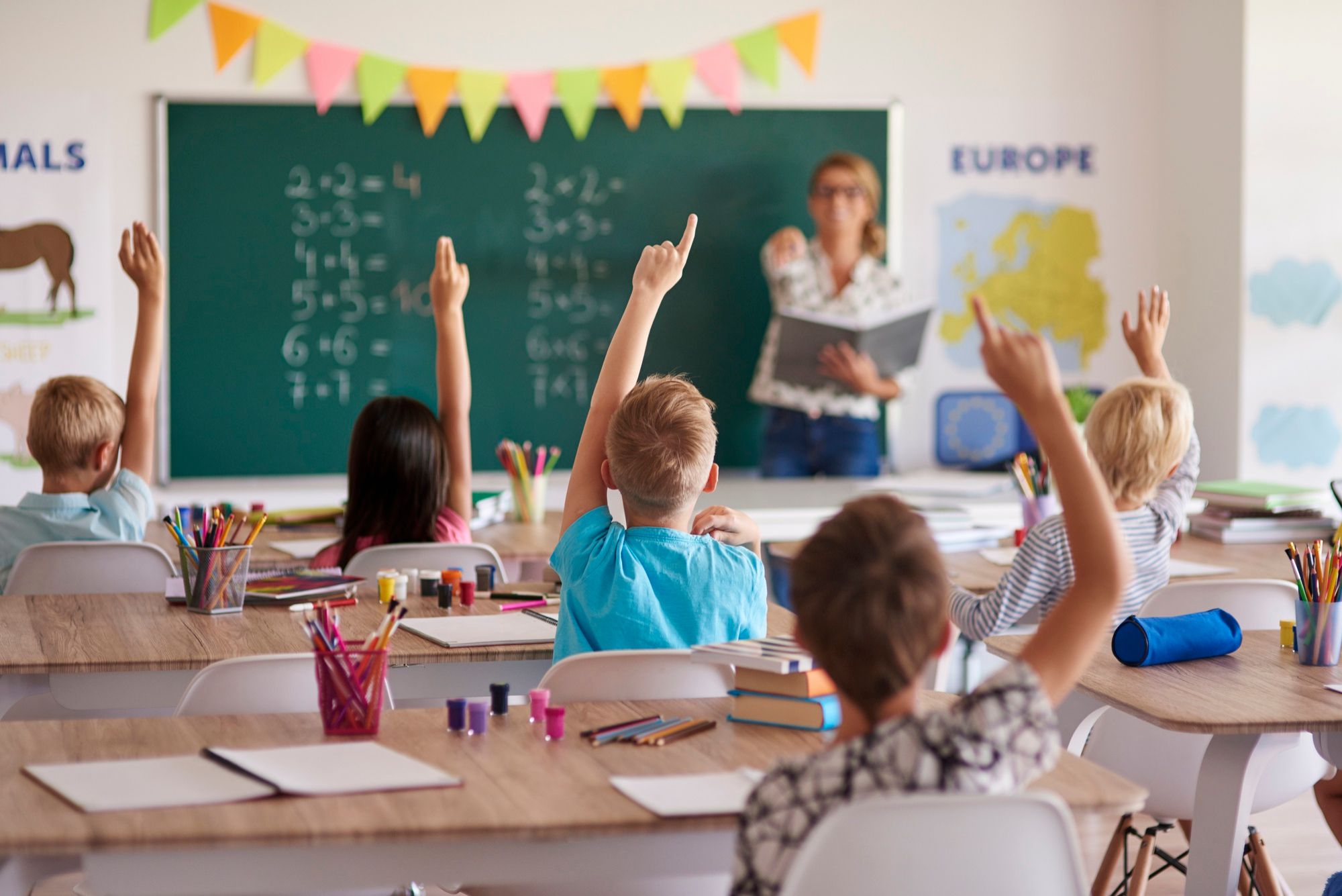 Varios alumnos levantan la mano durante una clase de Matemáticas.
