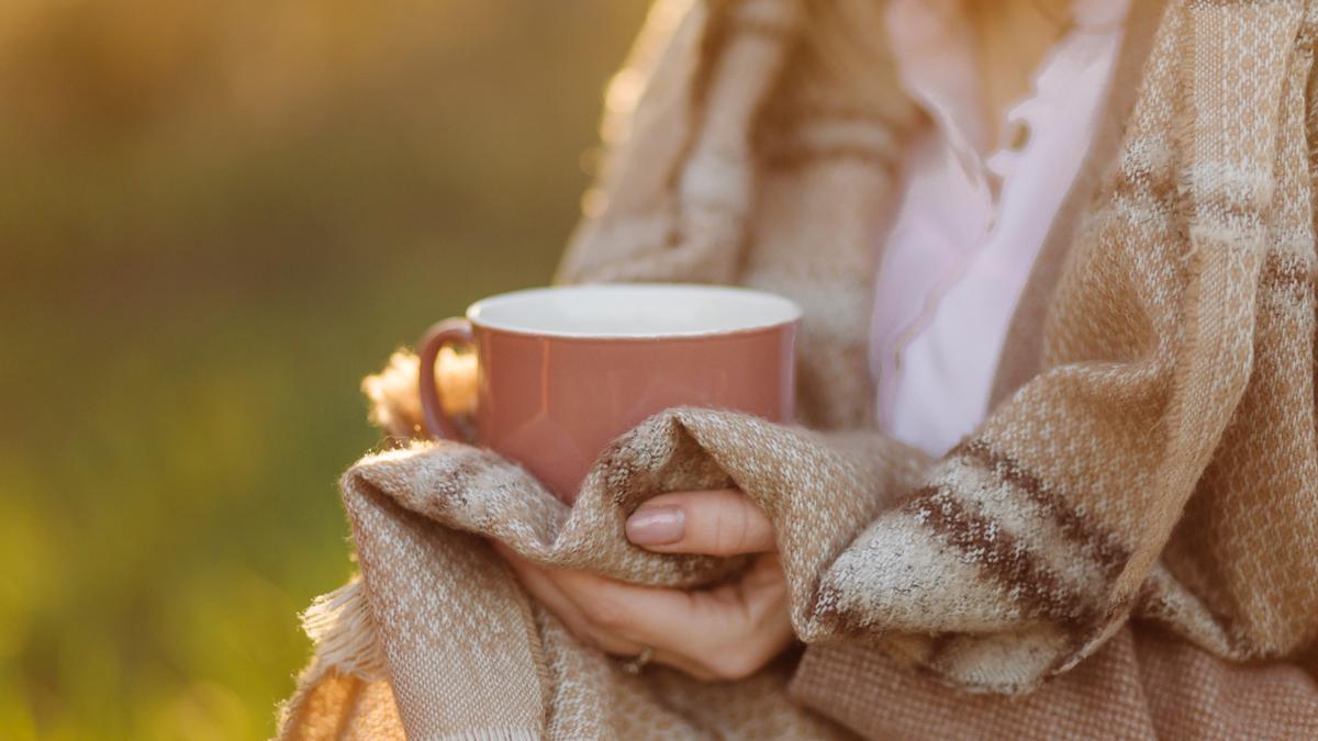 Una mujer con las manos frías sujeta una taza caliente.