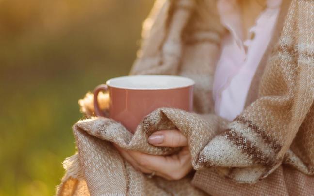 Una mujer con las manos fr&iacute;as sujeta una taza caliente.