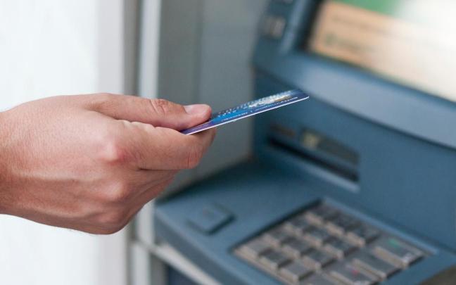 Una persona se dispone a sacar dinero de un cajero. Una persona se dispone a sacar dinero de un cajero.