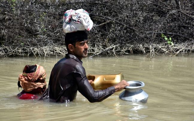 Un hombre y una mujer atraviesan una zona inundada en Karachi, la capital original de Pakistán. Un hombre y una mujer atraviesan una zona inundada en Karachi, la capital original de Pakistán.