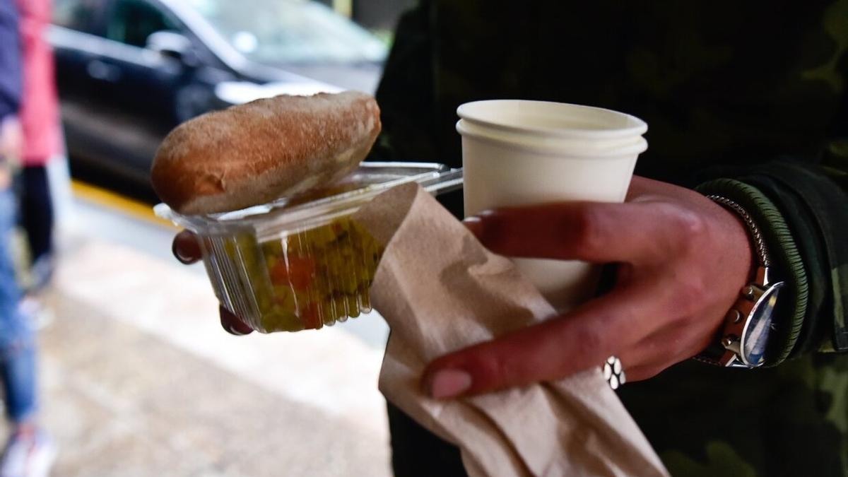 Alimentos entregados a un joven que acude a recibir una cena solidaria.