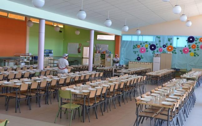 Una trabajadora prepara las mesas de un comedor escolar Una trabajadora prepara las mesas de un comedor escolar