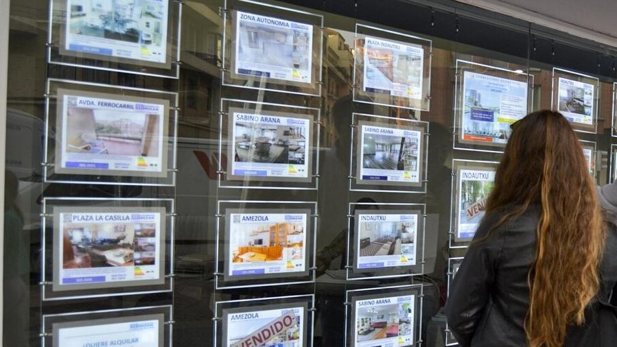 Una joven contempla el escaparate de una inmobiliaria.