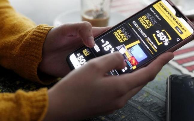 Una joven consulta las ofertas del Black Friday de un comercio en su teléfono móvil.