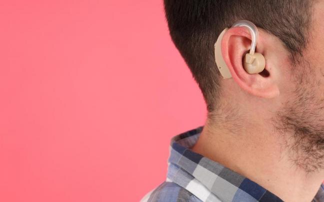 Un hombre joven lleva un aud&iacute;fono en la oreja.