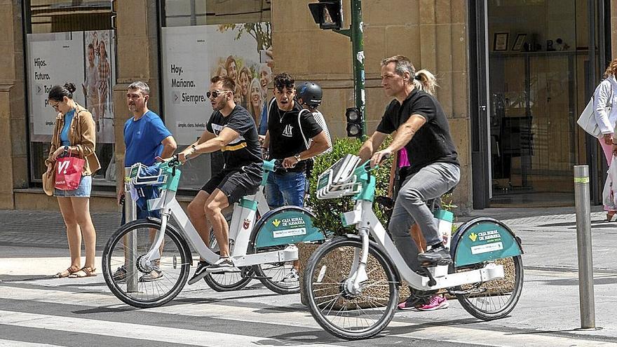 Dos usuarios de la red de alquiler de bicis eléctricas de Pamplona cruzan la calle Cortes de Navarra. | FOTO: PATXI CASCANTE