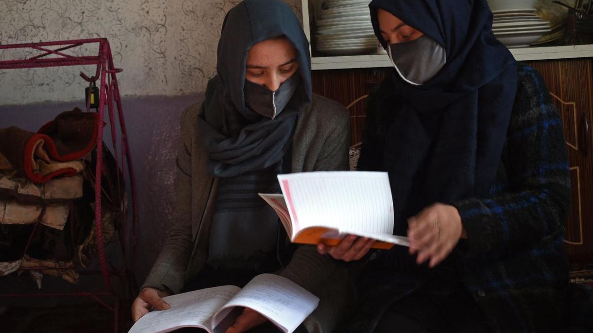 Dos jóvenes estudiantes leen un libro en su casa de Kabul.
