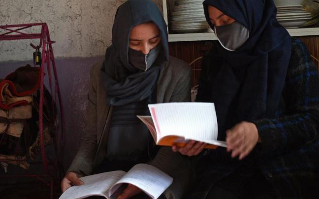 Dos jóvenes estudiantes leen un libro en su casa de Kabul. Dos jóvenes estudiantes leen un libro en su casa de Kabul.