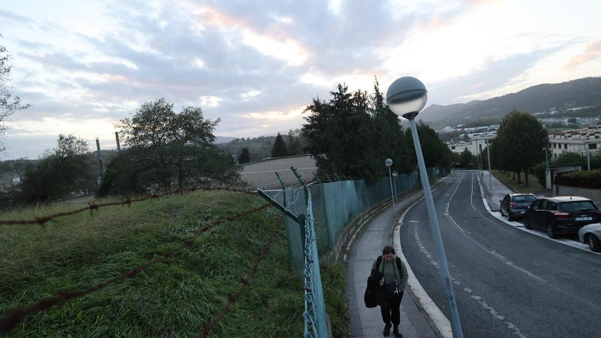 Una personas camina junto a la parcela del depósito del camino de los Pinos.