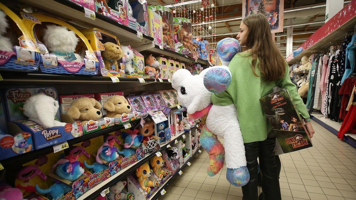 Una chica carga un peluche y un juego mientras busca más juguetes para celebrar la llegada de los Reyes Magos.