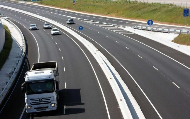 Varios vehículos circulan por una vía de doble carril. Varios vehículos circulan por una vía de doble carril.