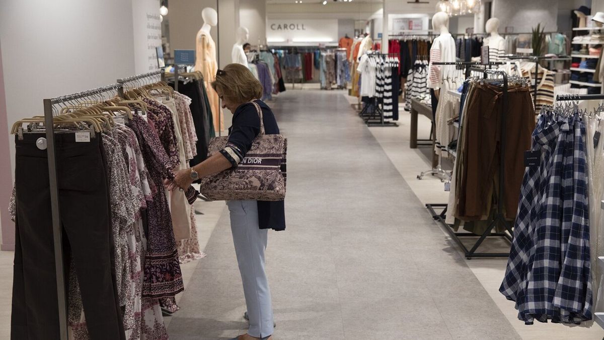 Una mujer observa prendas en un comercio en rebajas.