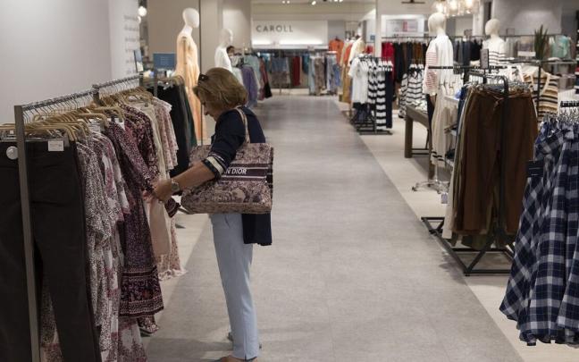 Una mujer observa prendas en un comercio en rebajas. Una mujer observa prendas en un comercio en rebajas.