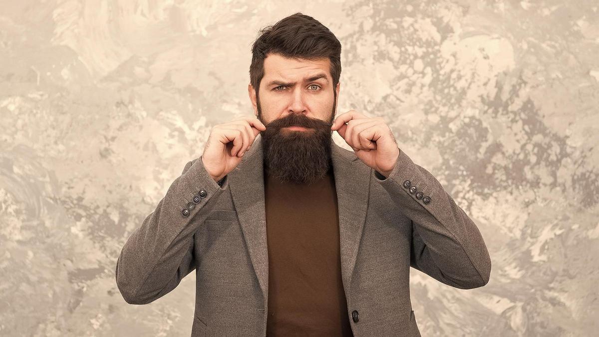 Un hombre retuerce los extremos de su bigote.