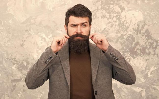 Un hombre retuerce los extremos de su bigote.