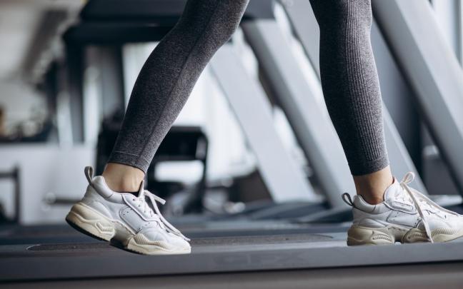 Una mujer hace ejercicio en la cinta de un gimnasio. Una mujer hace ejercicio en la cinta de un gimnasio.