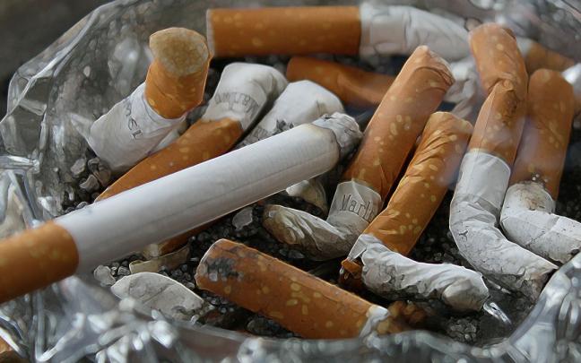 Imagen de un cigarro y varias colillas dentro de un cenicero. Imagen de un cigarro y varias colillas dentro de un cenicero.