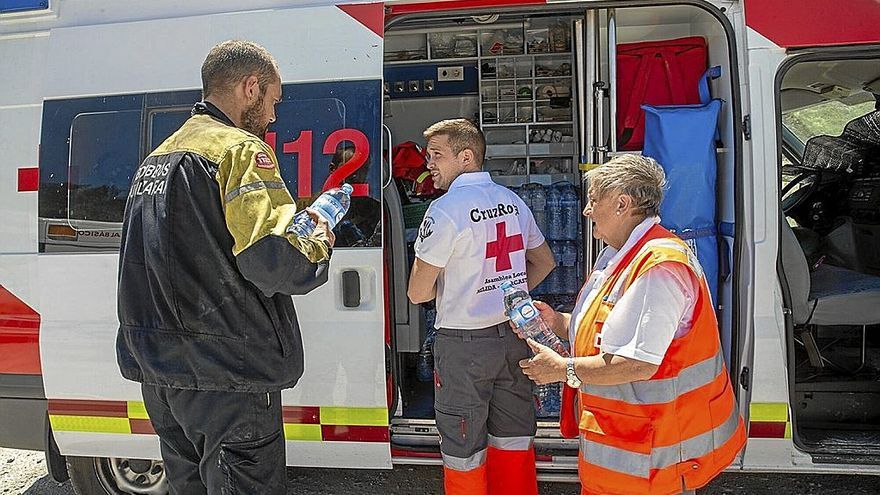 Voluntarios de Cruz Roja entregan agua y comida a uno de los bomberos que trabajan en Cascastillo.