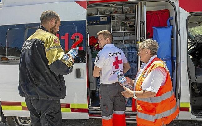Voluntarios de Cruz Roja entregan agua y comida a uno de los bomberos que trabajan en Cascastillo.