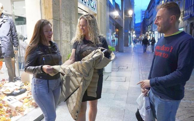 Dos turistas gaditanos se interesan por una prenda de abrigo en una de las tiendas de ropa más emblemáticas de las Siete Calles.