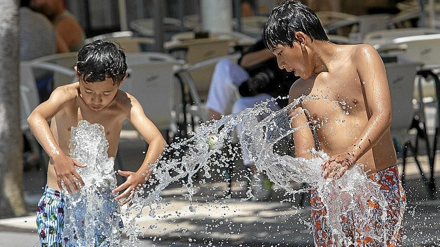 Dos niños juegan con el agua de las fuentes de la Plaza Yamaguchi.