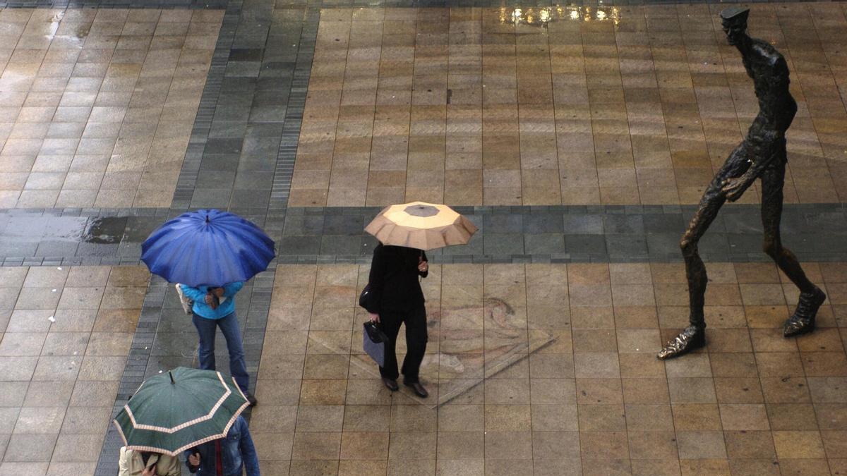 A la derecha, imagen de la estatua ''El Caminante'', en un día de lluvia en Vitoria-Gasteiz.