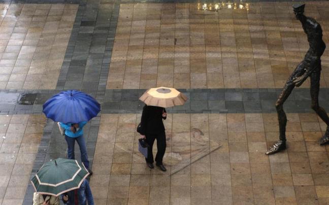 A la derecha, imagen de la estatua ''El Caminante'', en un día de lluvia en Vitoria-Gasteiz.