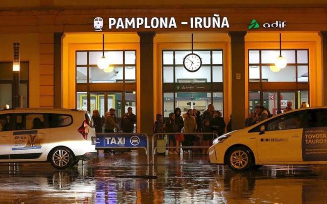 Viajeros de noche esperando la llegada de taxis delante de la estación de tren. Viajeros de noche esperando la llegada de taxis delante de la estación de tren.