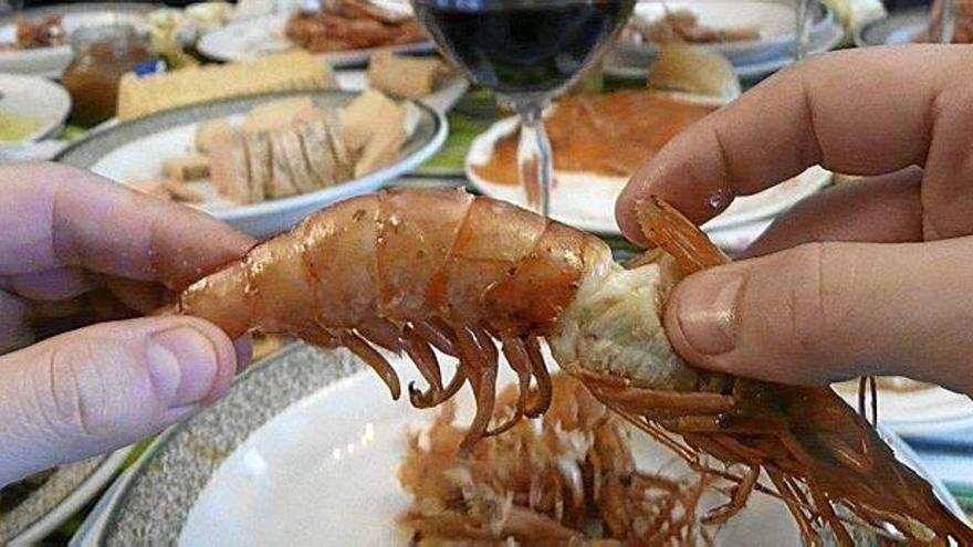 Una persona come un langostino, producto habitual en las comilonas de Navidad.