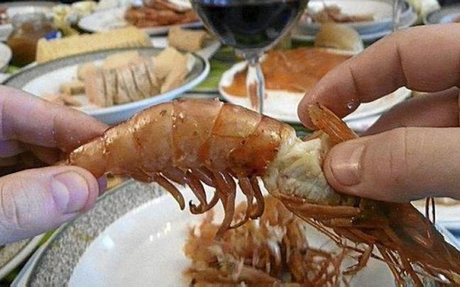 Una persona come un langostino, producto habitual en las comilonas de Navidad.