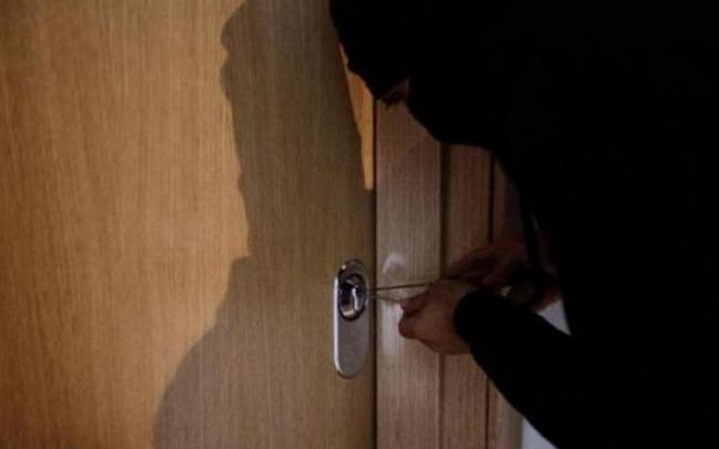 Montaje de un ladrón intentando entrar a una vivienda forzando la puerta con una ganzúa.