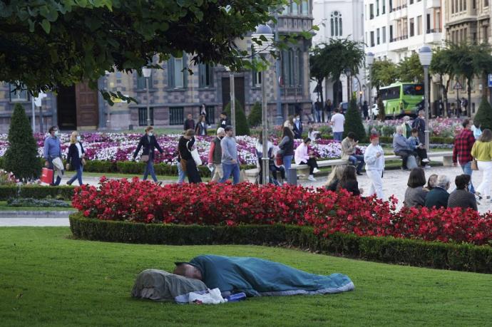 Una persona descansando en una zona ajardinada del centro de Bilbao.