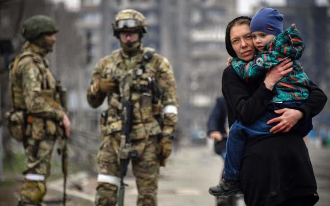 Una mujer abraza a un niño junto a un grupo de soldados rusos en una calle de Mariúpol.