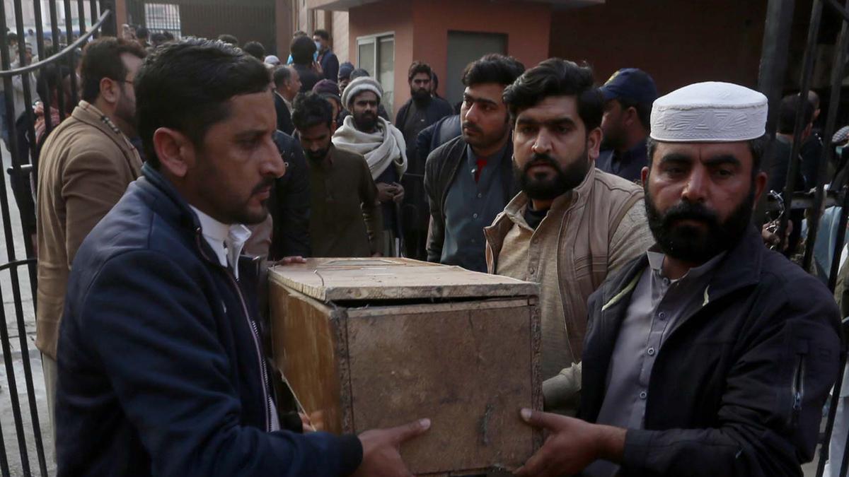 Varias personas trasladan uno de los cuerpos hallados tras el ataque suicida a una mezquita en Pakistán.