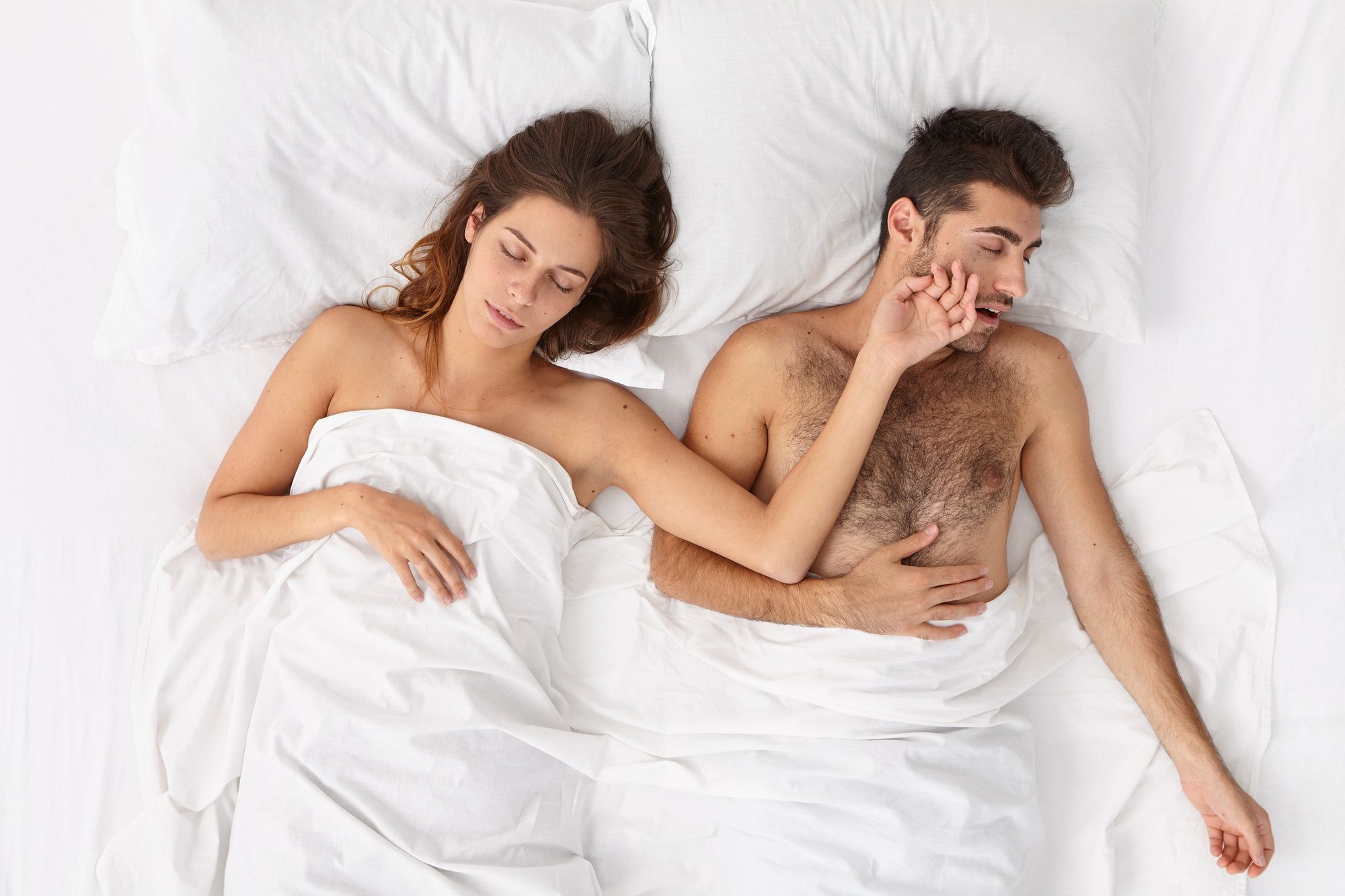 Una pareja acostada en la cama duerme plácidamente.