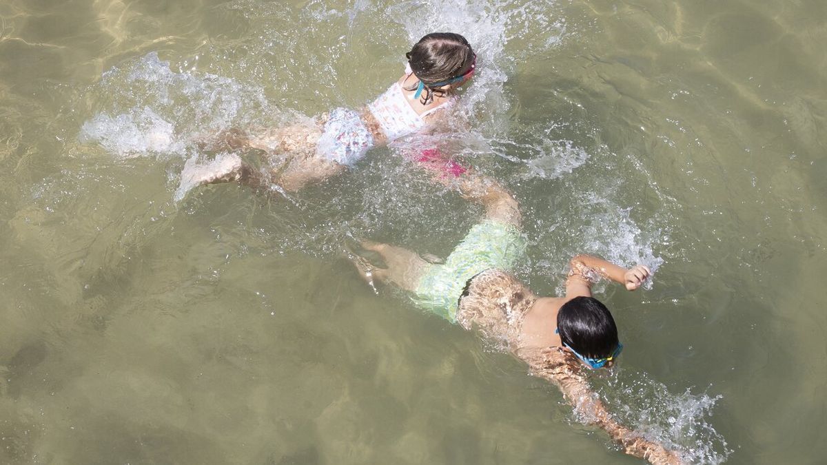 Dos niños se dan un chapuzón en la playa de La Concha de Donostia