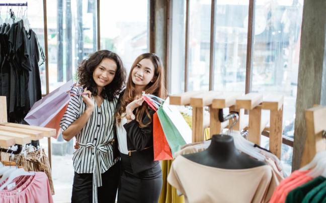 Dos amigas sonríen tras hacer sus compras en una tienda de ropa. Dos amigas sonríen tras hacer sus compras en una tienda de ropa.