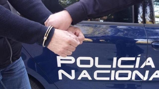 Un hombre es esposado y conducido por un agente de policía.