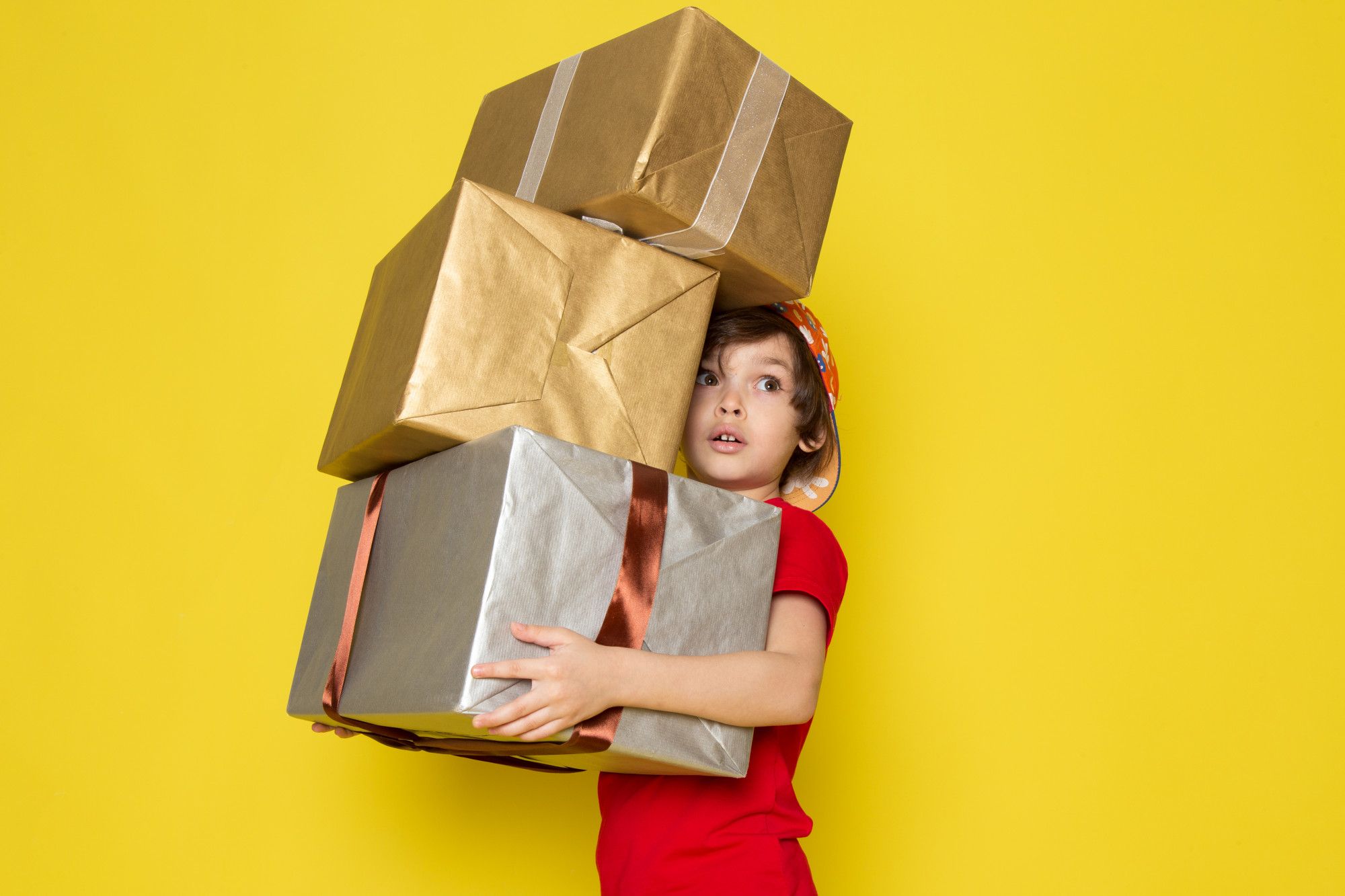 Un niño cargado con cajas de regalos.
