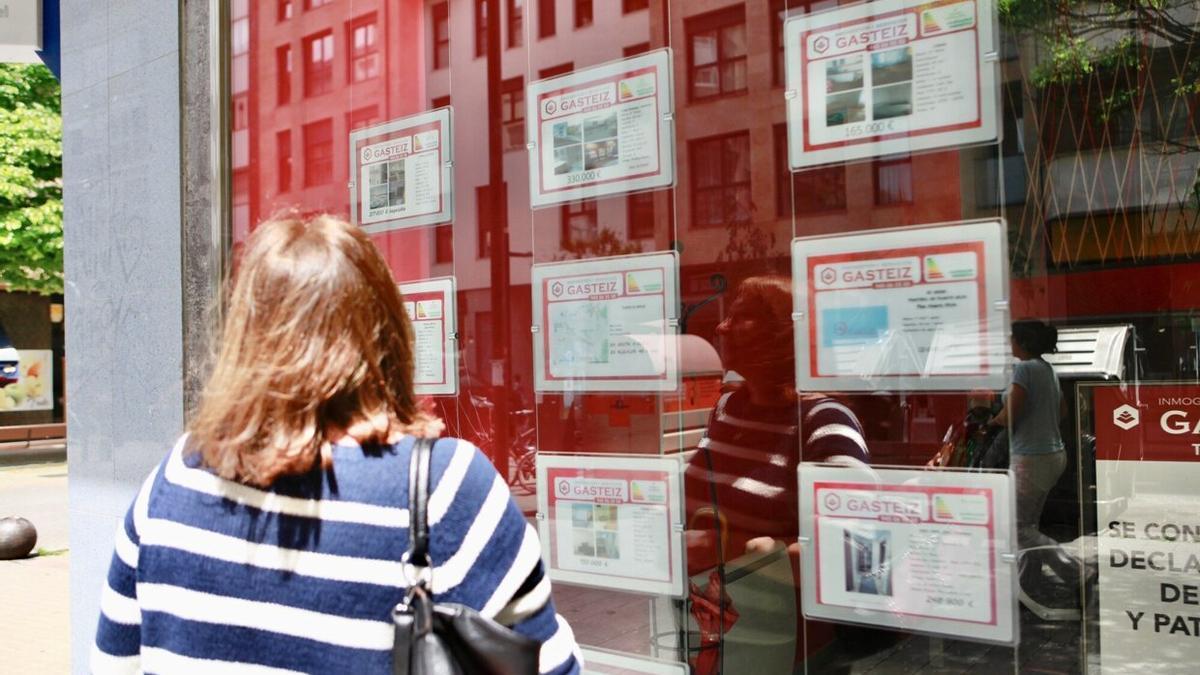 Una joven observa el escaparate de una inmobiliaria.