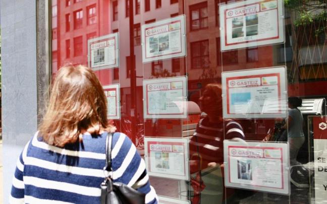 Una joven observa el escaparate de una inmobiliaria.