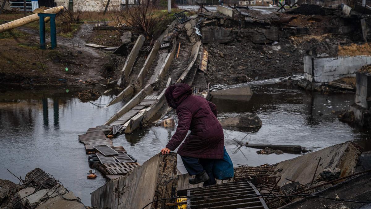 Una mujer trata de cruzar por un puente destruido en la ciudad de Bakhmut, en la región de Donetsk.