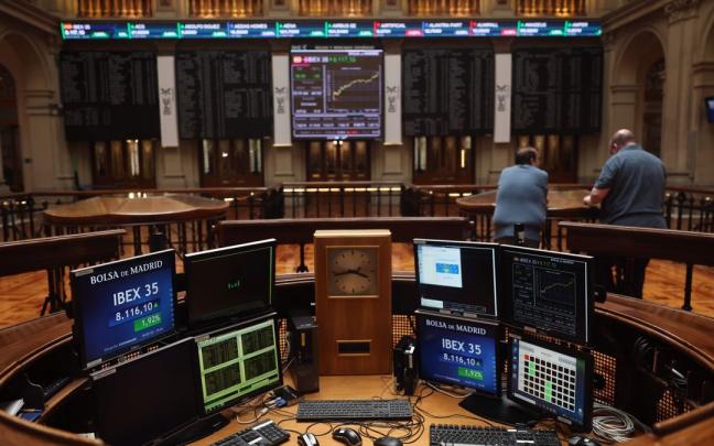 Dos personas miran los paneles de la Bolsa. Dos personas miran los paneles de la Bolsa.