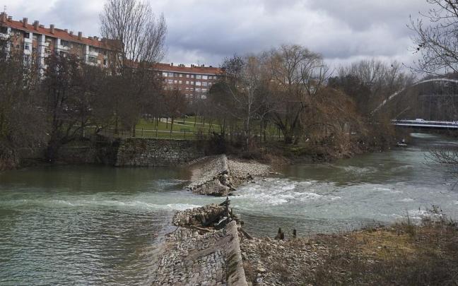 Vista de la presa de Santa Engracia en el río Arga, rota parcialmente desde 2018, y al fondo el puente de Oblatas.
