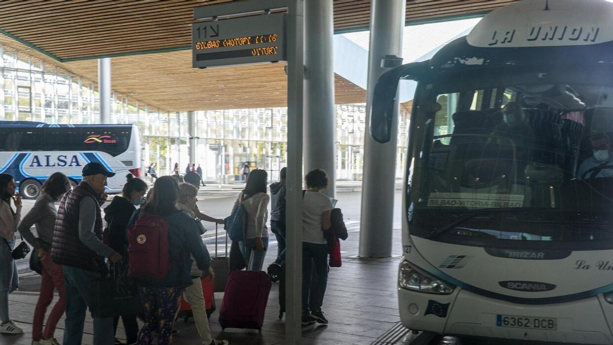 Varias personas esperan para subir a un autobús.