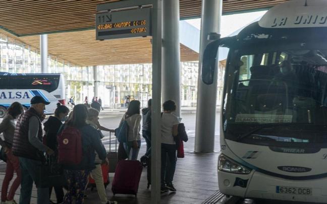 Varias personas esperan para subir a un autob&uacute;s.